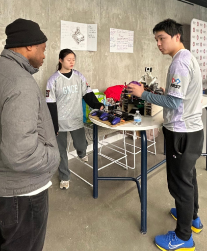 Team members explaining the robot to a visitor at Clark University