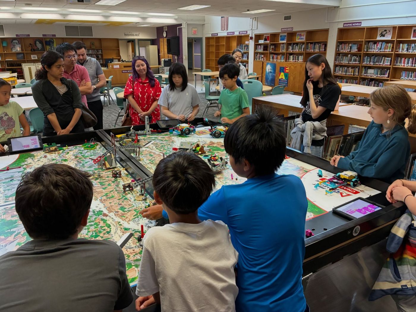 Campers and families gathered around the FLL table for the Friday showcase
