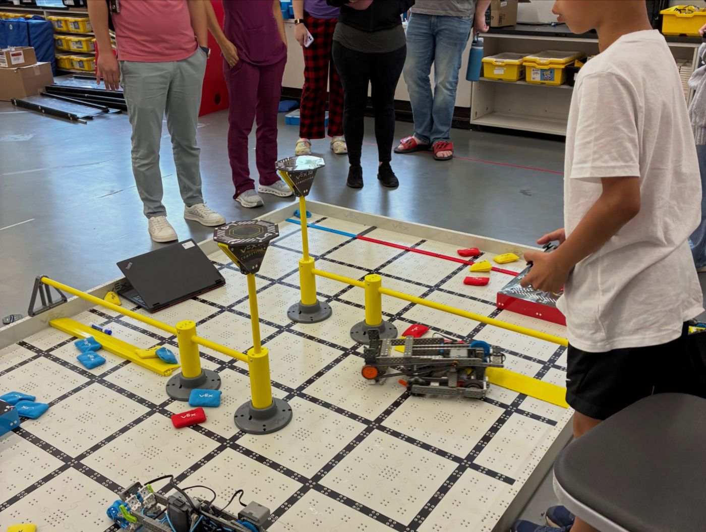 A camper driving a VEX IQ robot on the competition field